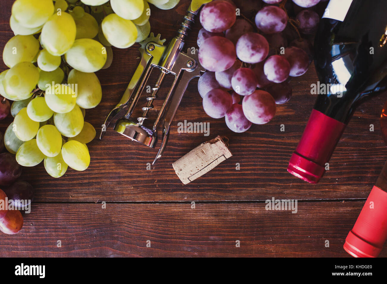 Des bouteilles de vin, tire-bouchon et raisin Vue de dessus sur fond de bois Banque D'Images