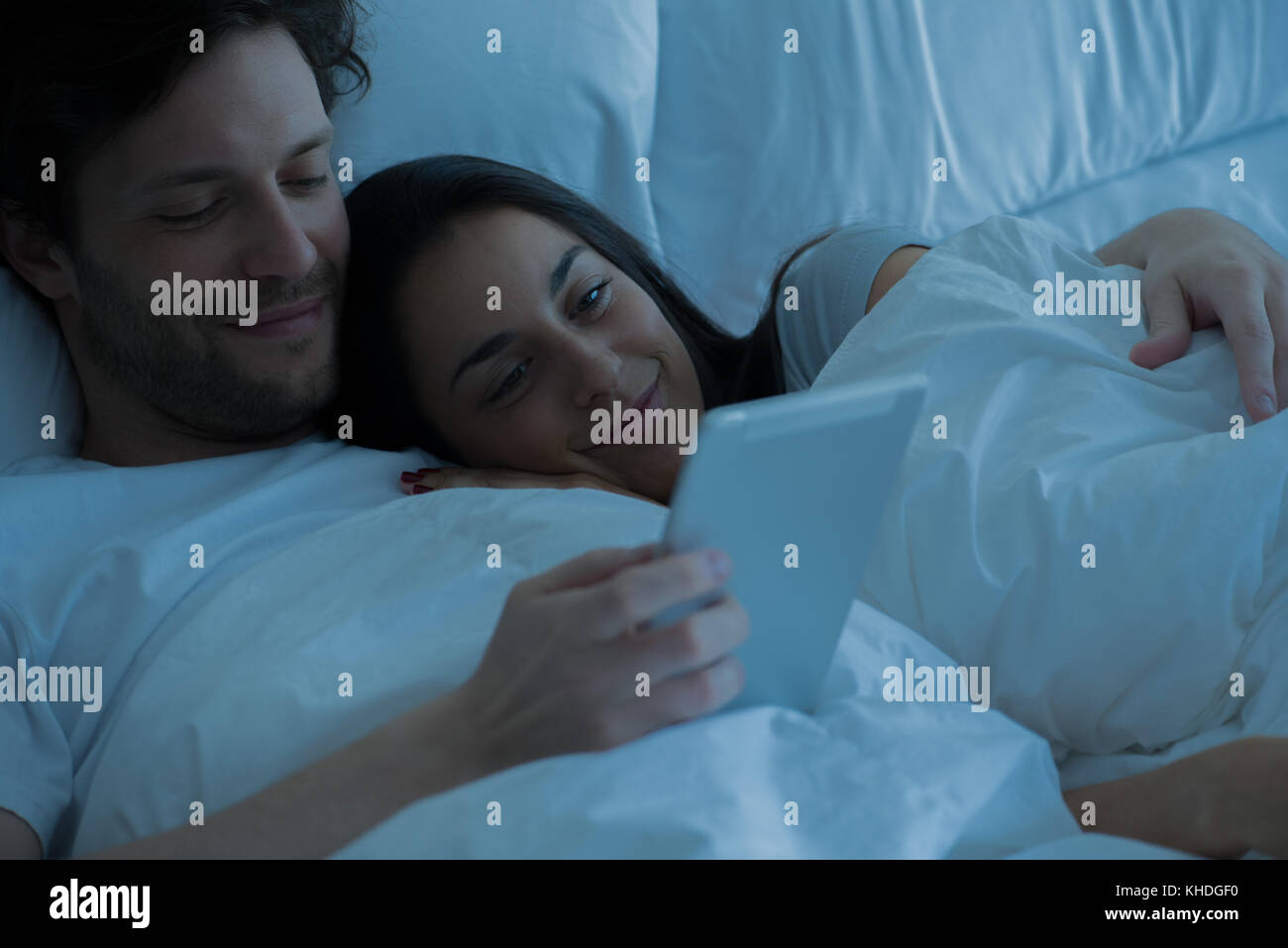 Couple using digital tablet in bed Banque D'Images