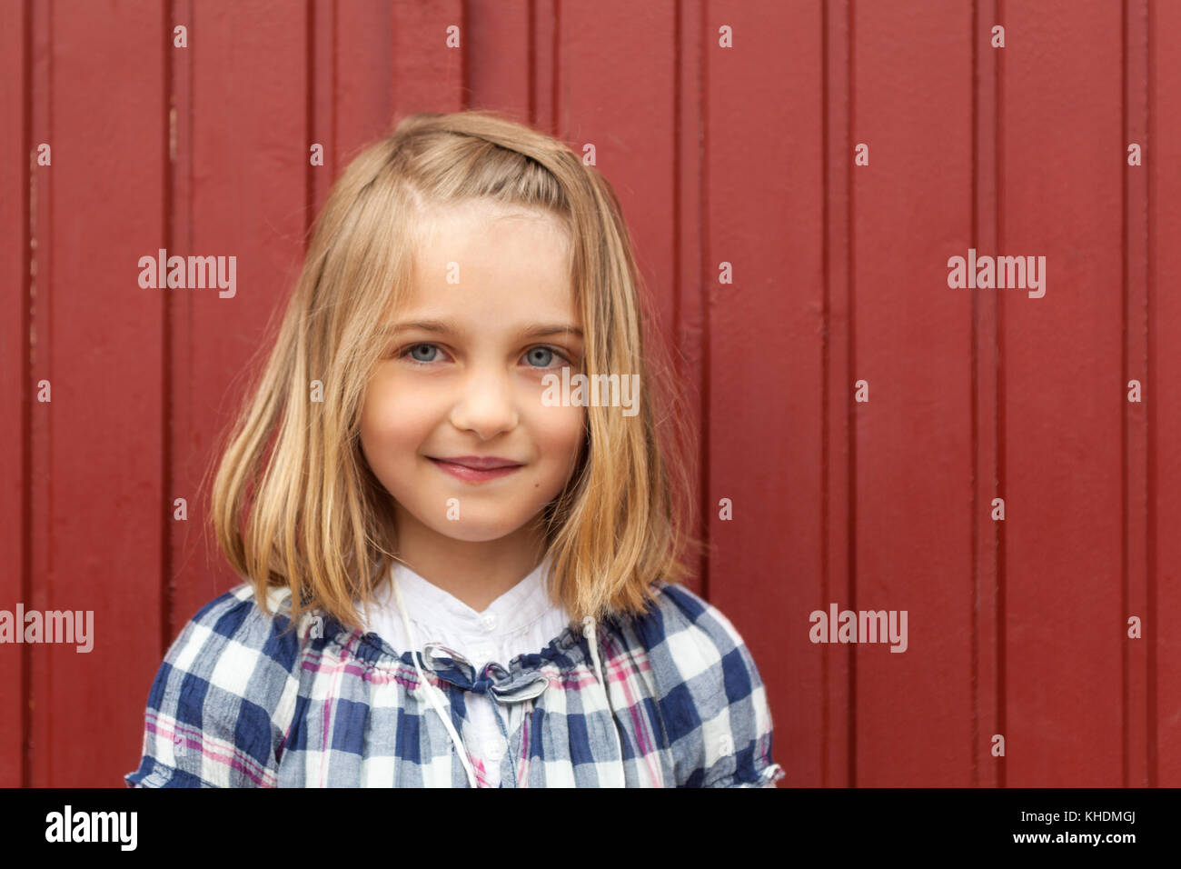 La tête et les épaules de plein air portrait de 7 ans, fille en face de fond de bois rouge Modèle Libération : Oui. Biens : Non. Banque D'Images