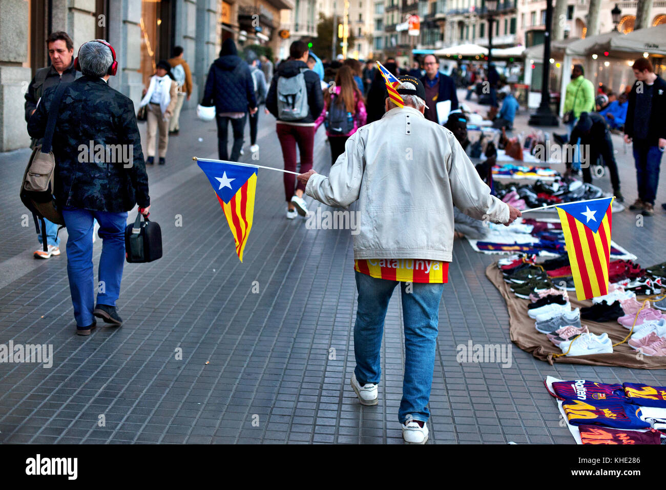 Homme marchant dans la rue en agitant des drapeaux de l'indépendance Catalane, Barcelone, Espagne. Banque D'Images