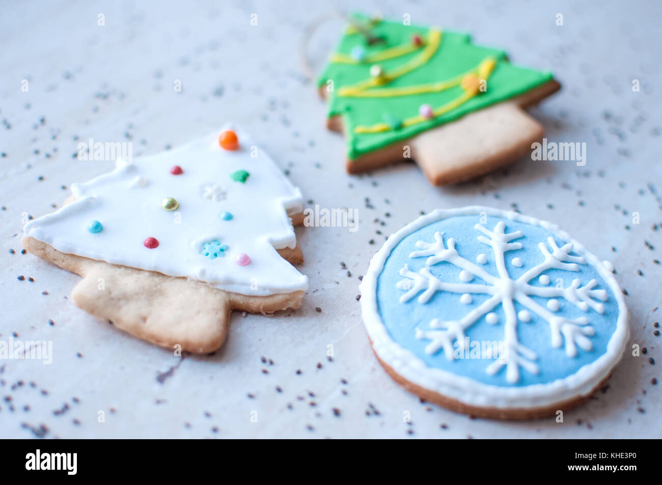 Deux gingerbread cookies dans la forme de la production d'arbres de Noël et d'un cookie dans la forme d'un round blue snowflake sur une table en bois et dispersés chia Banque D'Images