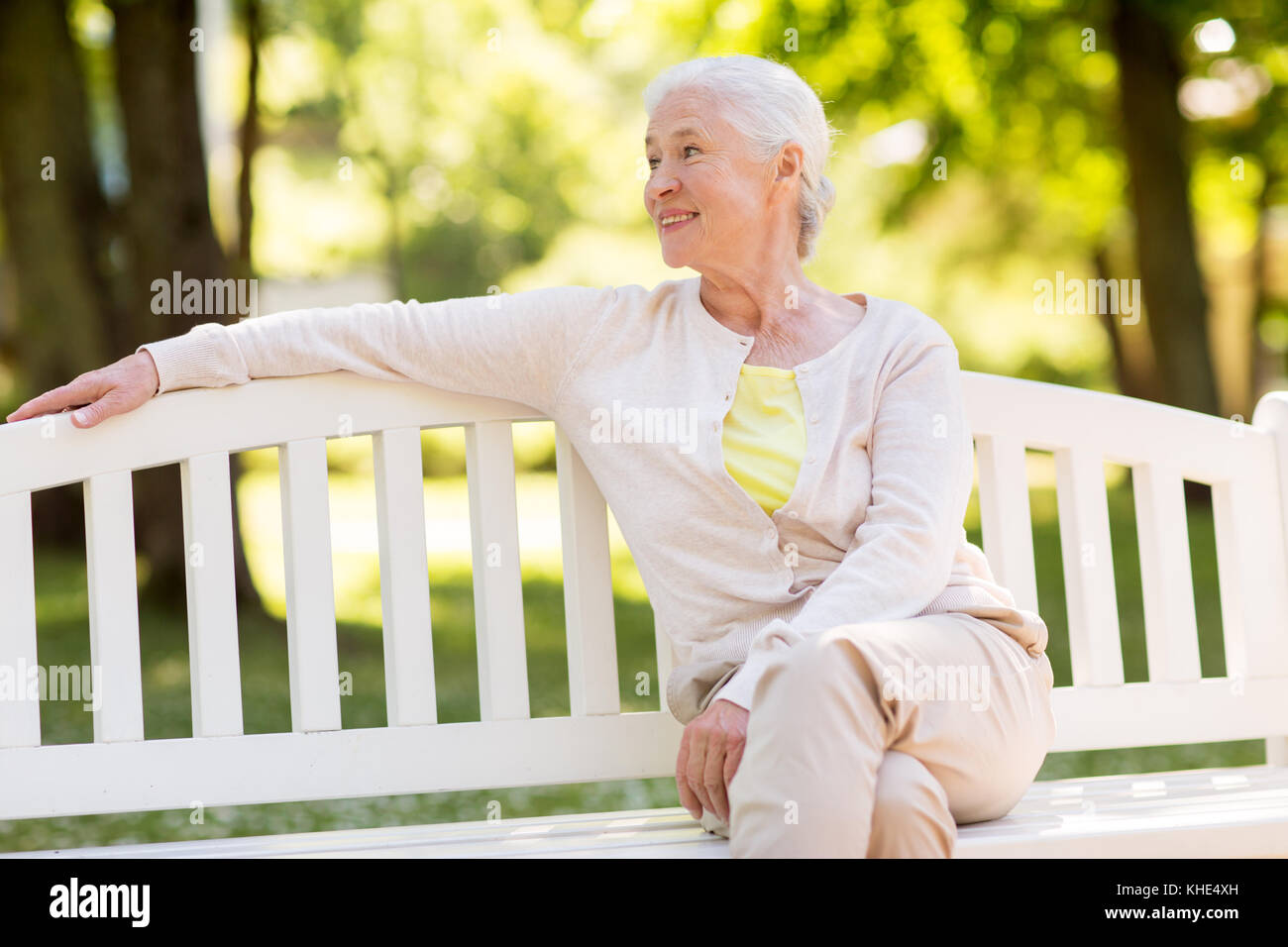 Happy senior femme assis sur un banc au parc d'été Banque D'Images