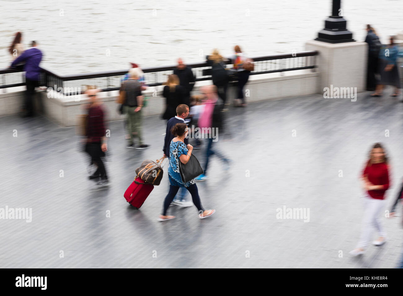 Londres, Royaume-Uni. Un couple avec une valise roulant marche le long de la rive sud de la Tamise. Banque D'Images