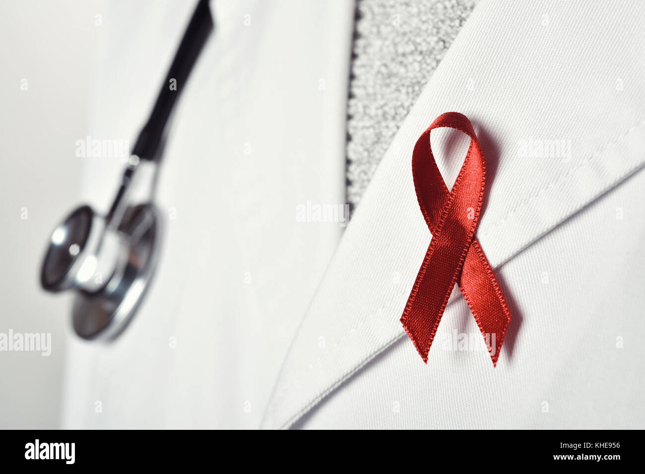 gros plan d'un jeune médecin caucasien avec un ruban rose épinglé dans le rabat de son manteau blanc, en solidarité avec les personnes vivant avec le VIH/SIDA Banque D'Images
