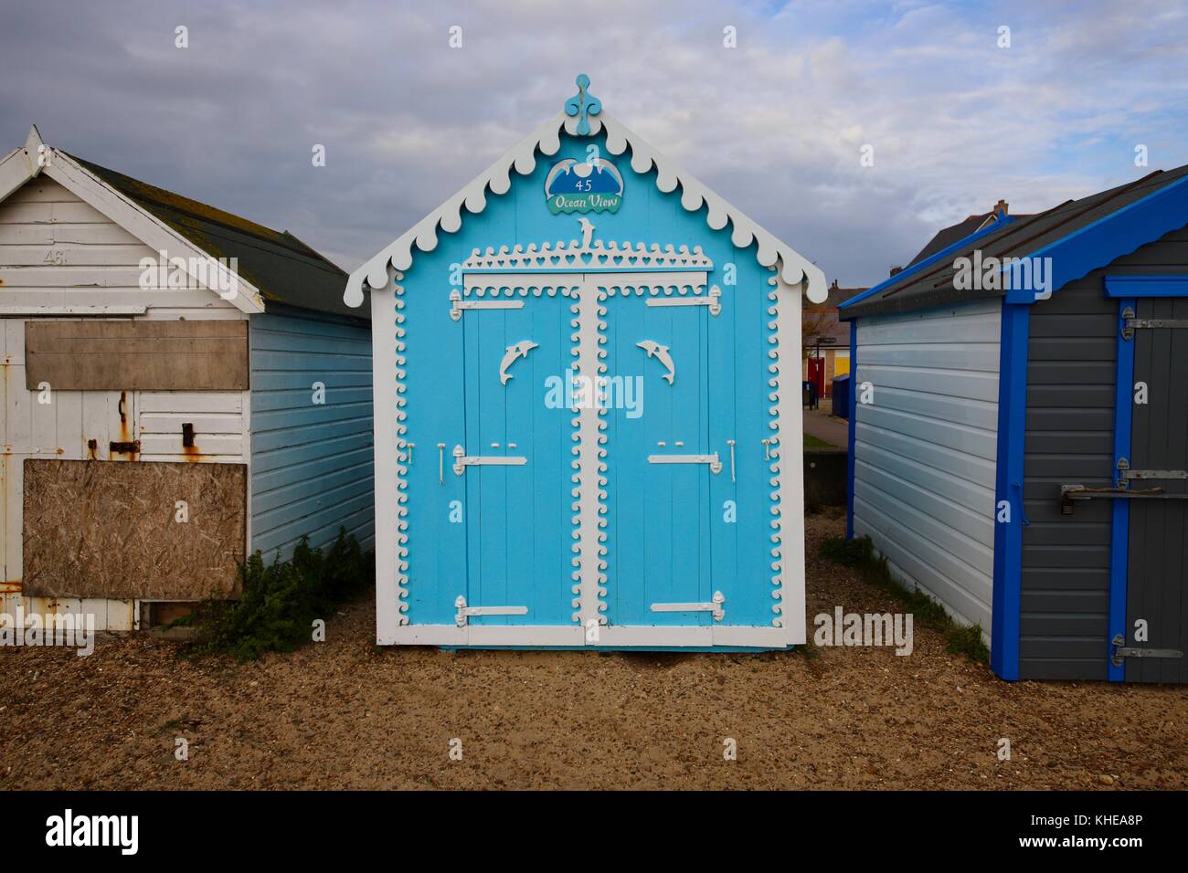 En bois blanc et bleu immaculé beach hut numéro 45 vue sur l'océan près de 46 qui est en mauvais état et barricadés. Près de parc Martello Felixstowe, Suffolk. Banque D'Images
