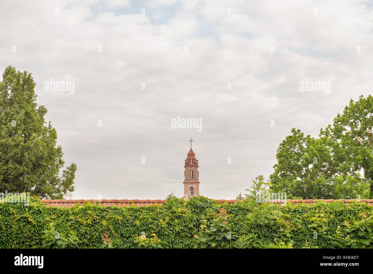 Clocher de l'église derrière le mur rouge Banque D'Images