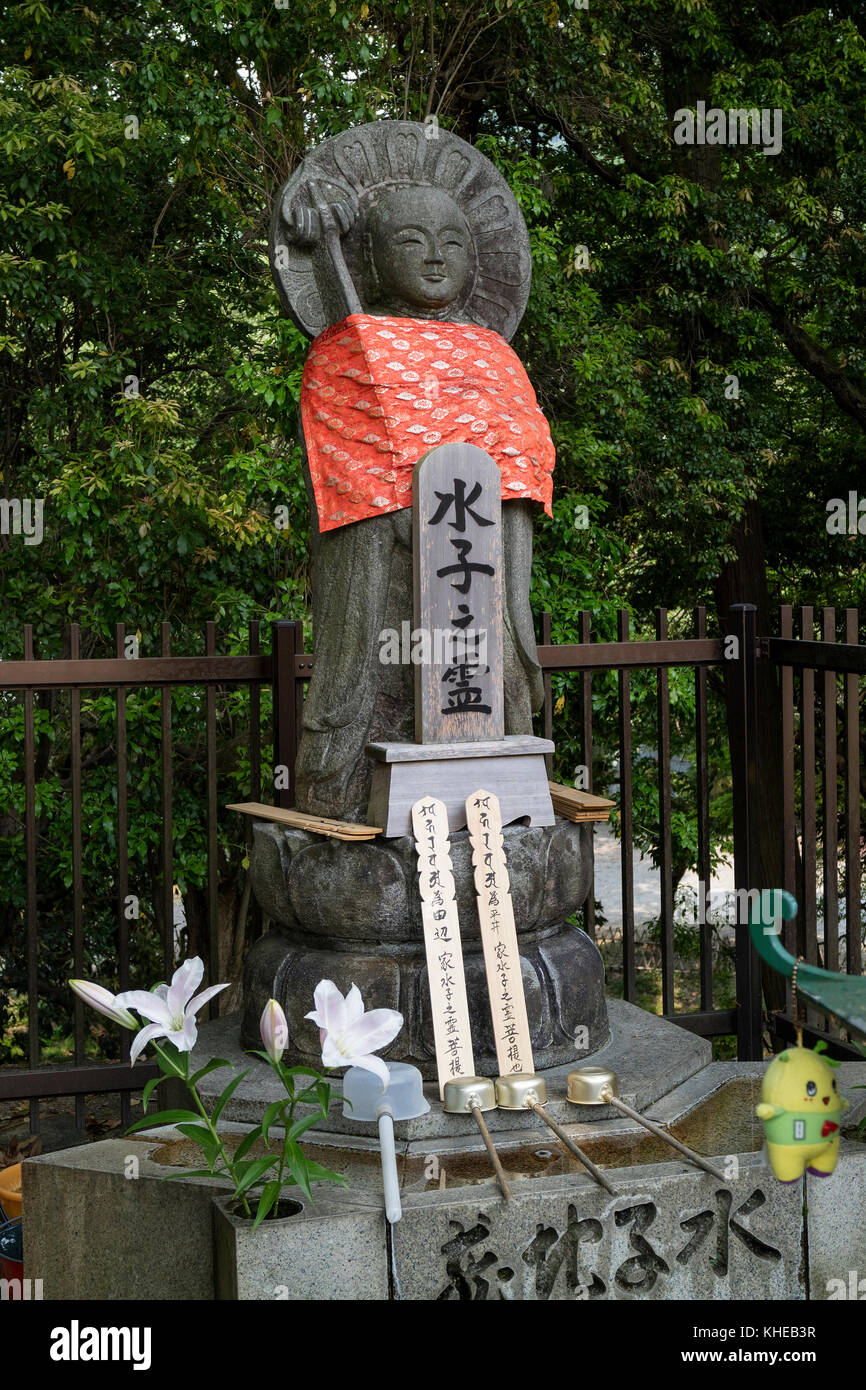 Nara, Japon - 31 mai 2017 : Pierre relegious pacifique statue jizo avec jupe rouge et un bassin de purification avec louches Banque D'Images