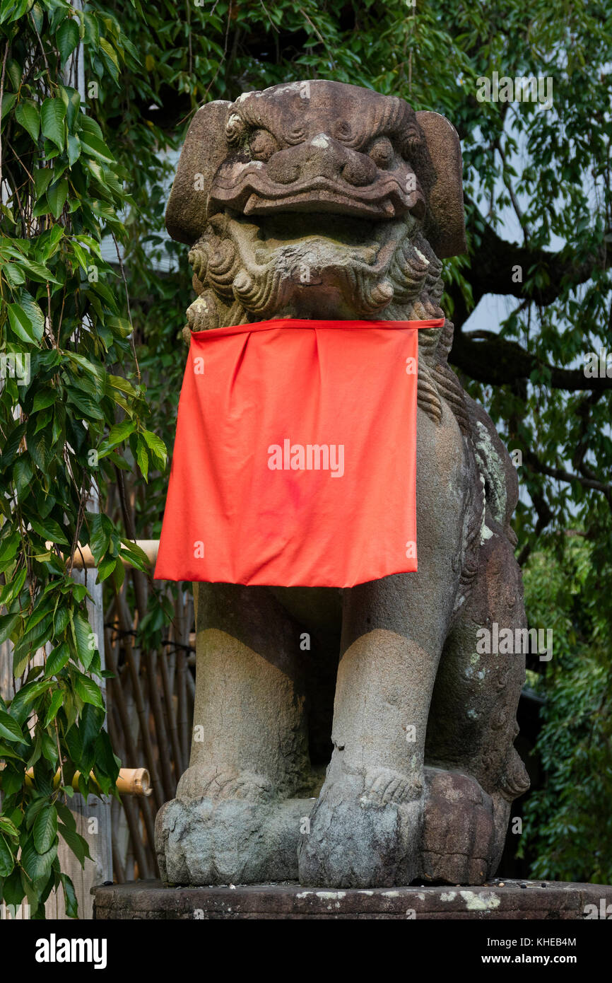 Nara, Japon - 31 mai 2017 : chien lion gardien en pierre, Komainu, avec une jupe rouge dans le parc de Nara Banque D'Images