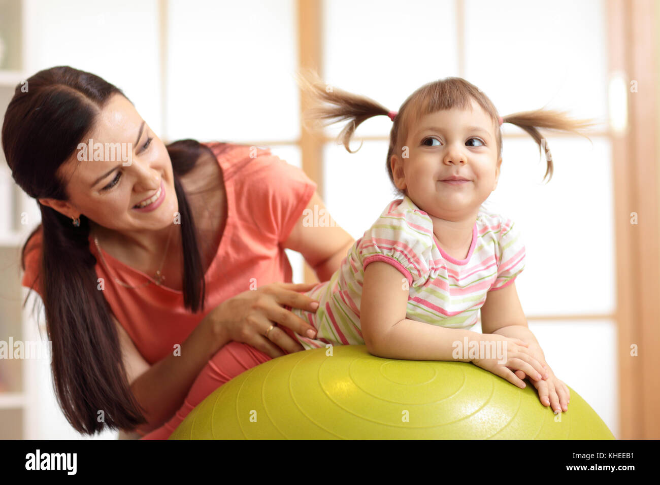 Mère et enfant fille jouant avec ballon de gymnastique à la maison Banque D'Images