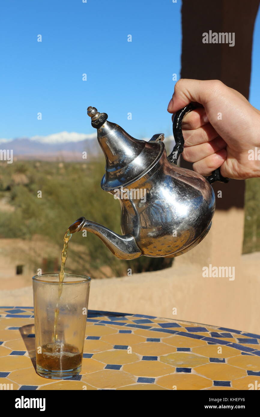 'Whiskey' berbère (thé à la menthe) d'être servi la façon traditionnelle à skoura, Maroc, avec une vue sur les montagnes de l'atlas en arrière-plan Banque D'Images