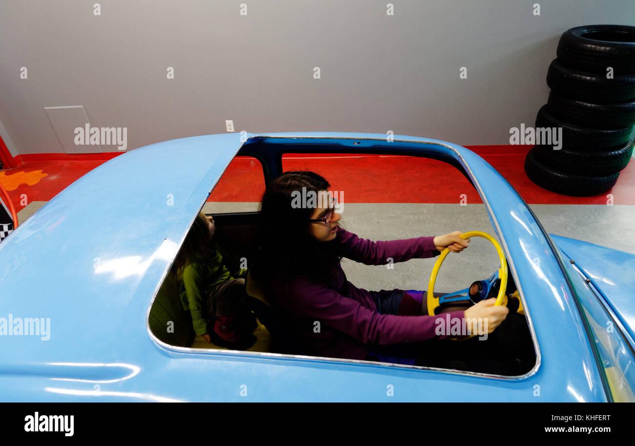 Une mère fait semblant de conduire une Fiat 500 dans le musée d'Enfance sur le thème de l'intérieur jouent cenrtre à Laval, Québec Banque D'Images