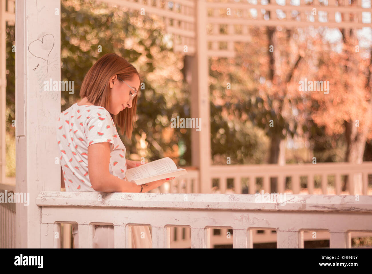 Une jeune femme lisant un livre à l'extérieur, portrait, journée ensoleillée, maison d'été Banque D'Images