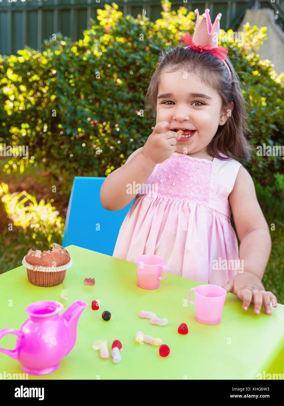 Happy baby girl, manger gummies rire et sourire dans l'air extérieur tea party habillé en robe rose comme la princesse ou la reine avec couronne Banque D'Images