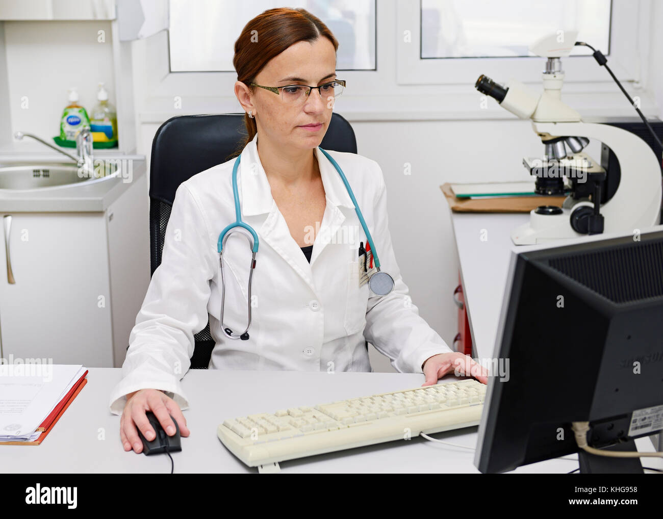 Un médecin travaillant sur un ordinateur à son bureau Banque D'Images