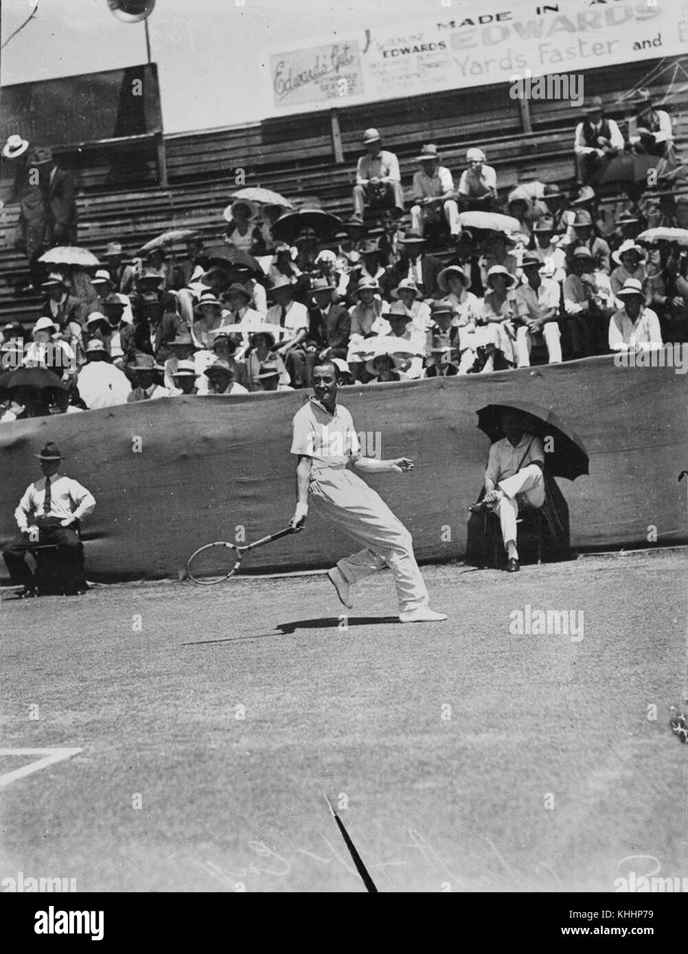 Cette image capture Patrick Hughes lors d'un match de tennis en 1933, où il affrontait un adversaire australien. Le moment reflète l'esprit de compétition du tennis international au début du XXe siècle, soulignant la portée mondiale du sport. Banque D'Images