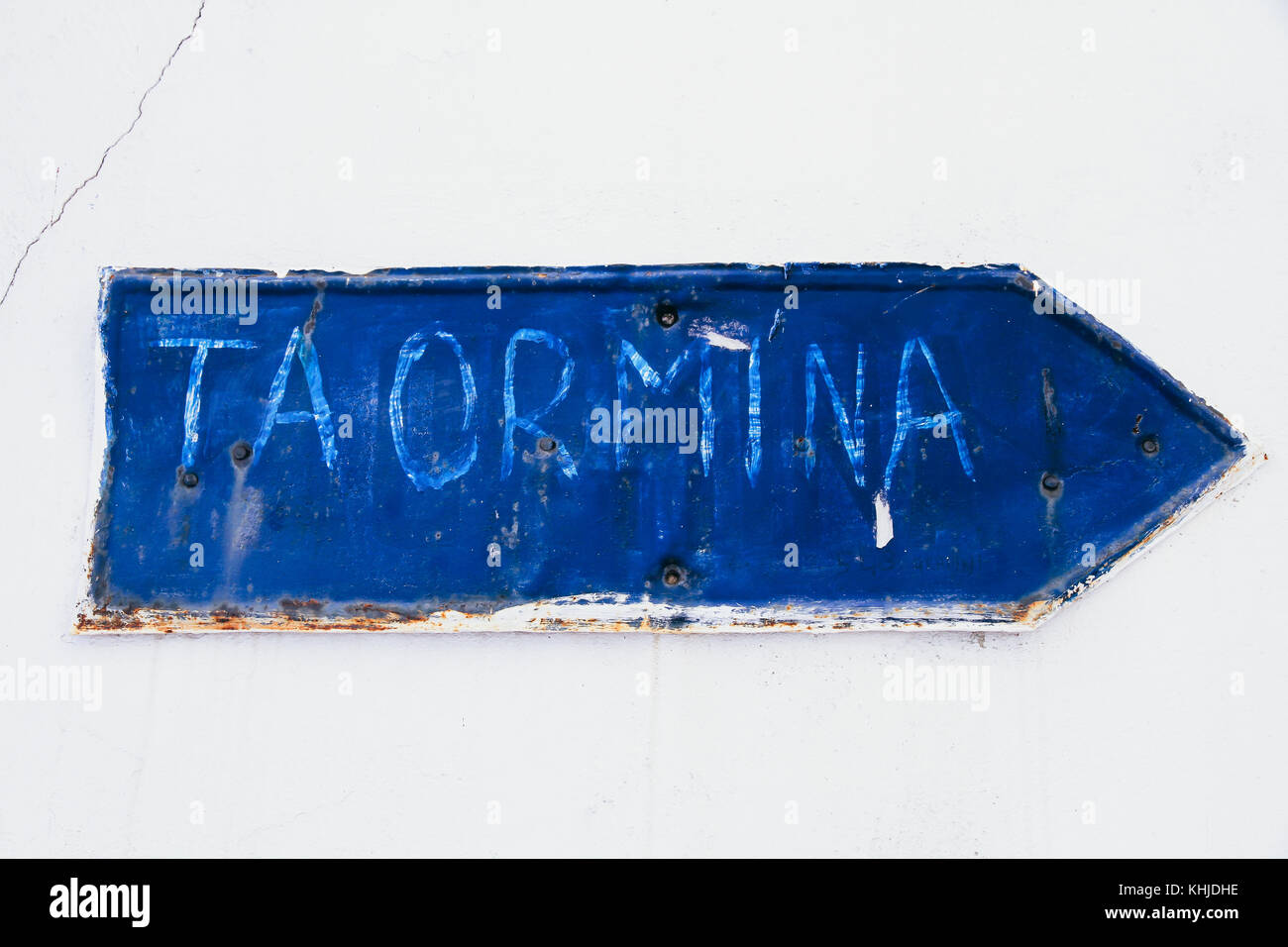 Taormina écrite manuellement dans un blue rusty et grunge metal plaque de fer flèche avec revêtement de déroulage et rayures texture fixé sur un mur de chaux Banque D'Images