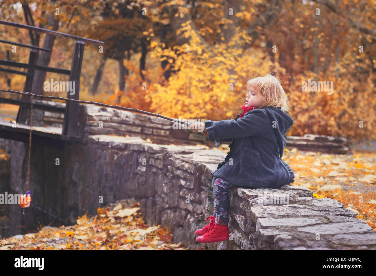 Belle petite fille jouant avec une direction générale de la pêche et les poissons, de jouets dans le parc par une froide journée d'automne Banque D'Images