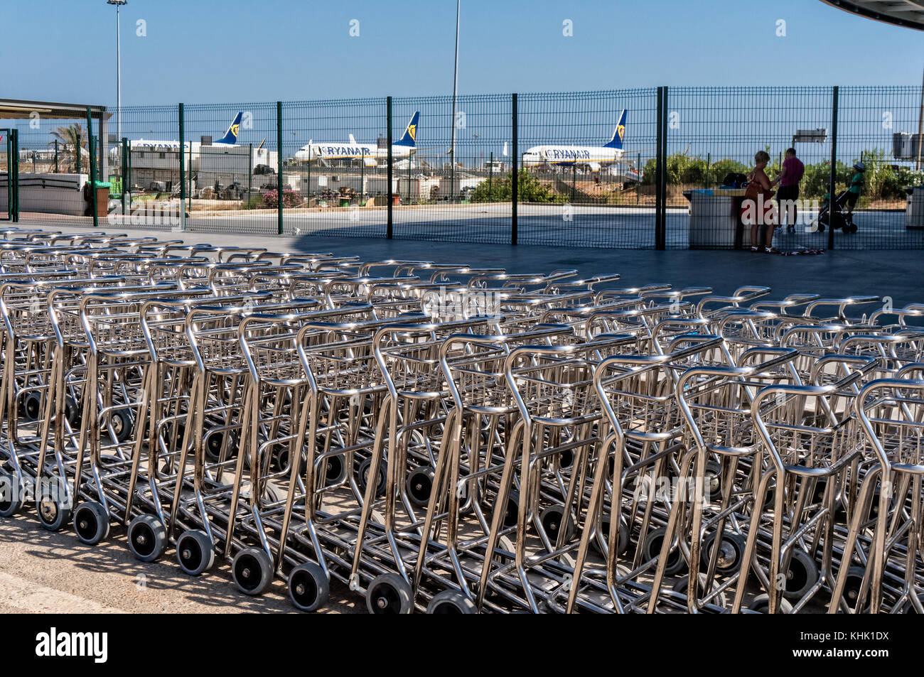 Longue rangée avec chariots à bagages à l'aéroport de Faro au Portugal (Algarve) avions de Ryanair avec en arrière-plan. Banque D'Images