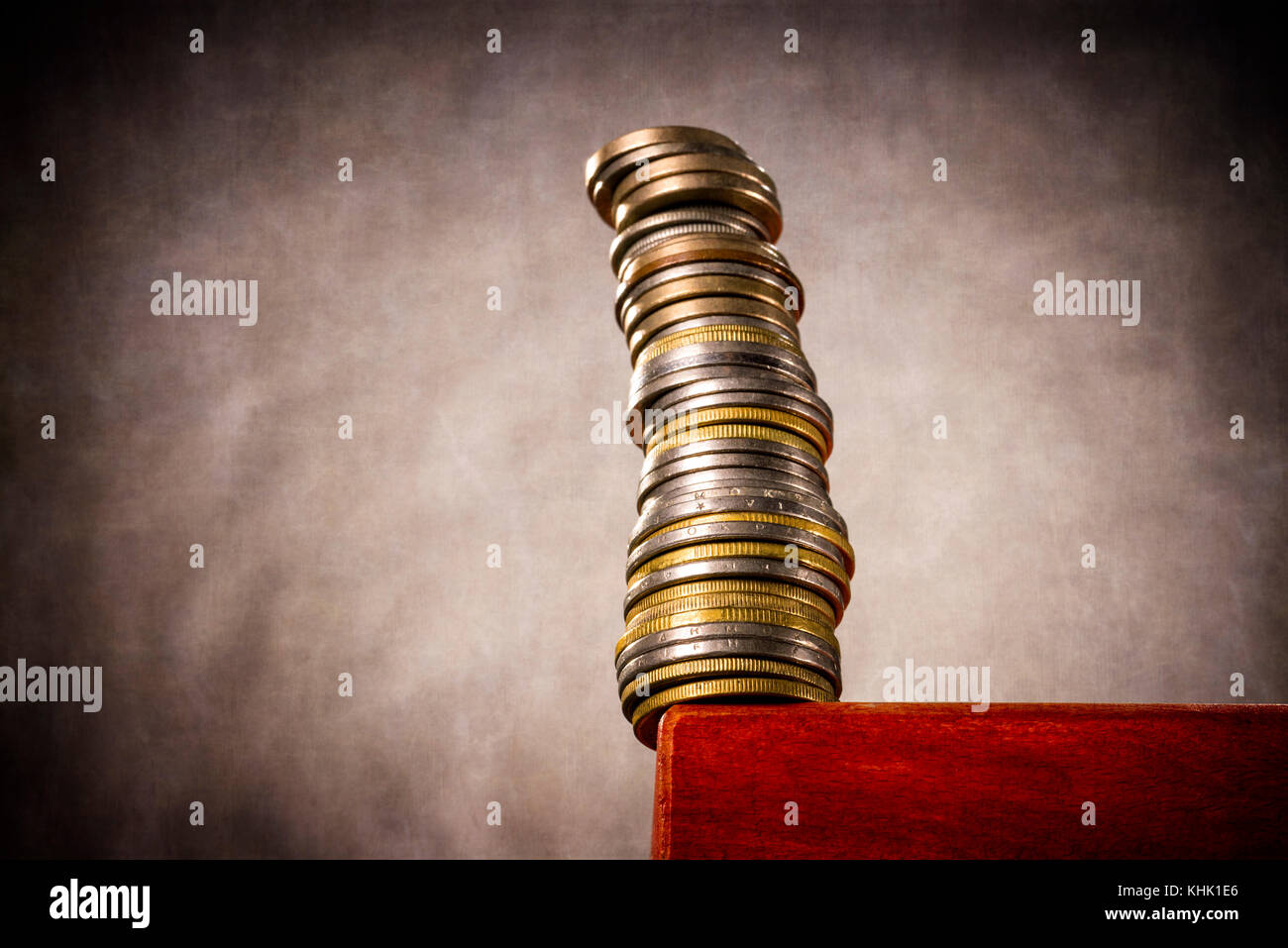 Une grande pile de pièces est à un bord de la table et menace de tomber en panne. Banque D'Images