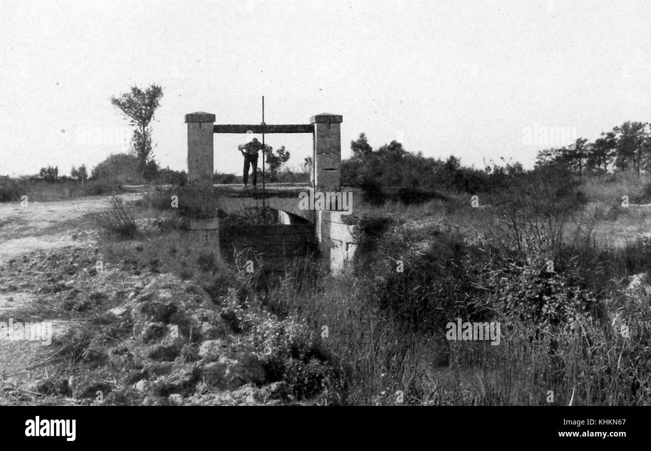 Une photo d'un homme l'exploitation d'une écluse, la porte est partie d'un système qui permet à des agriculteurs locaux pour évacuer l'excès d'eau de la région à la fin de l'hiver et au début du printemps, la saleté et les petites usines composent le paysage, Camargue, France, juillet, 1922. Banque D'Images