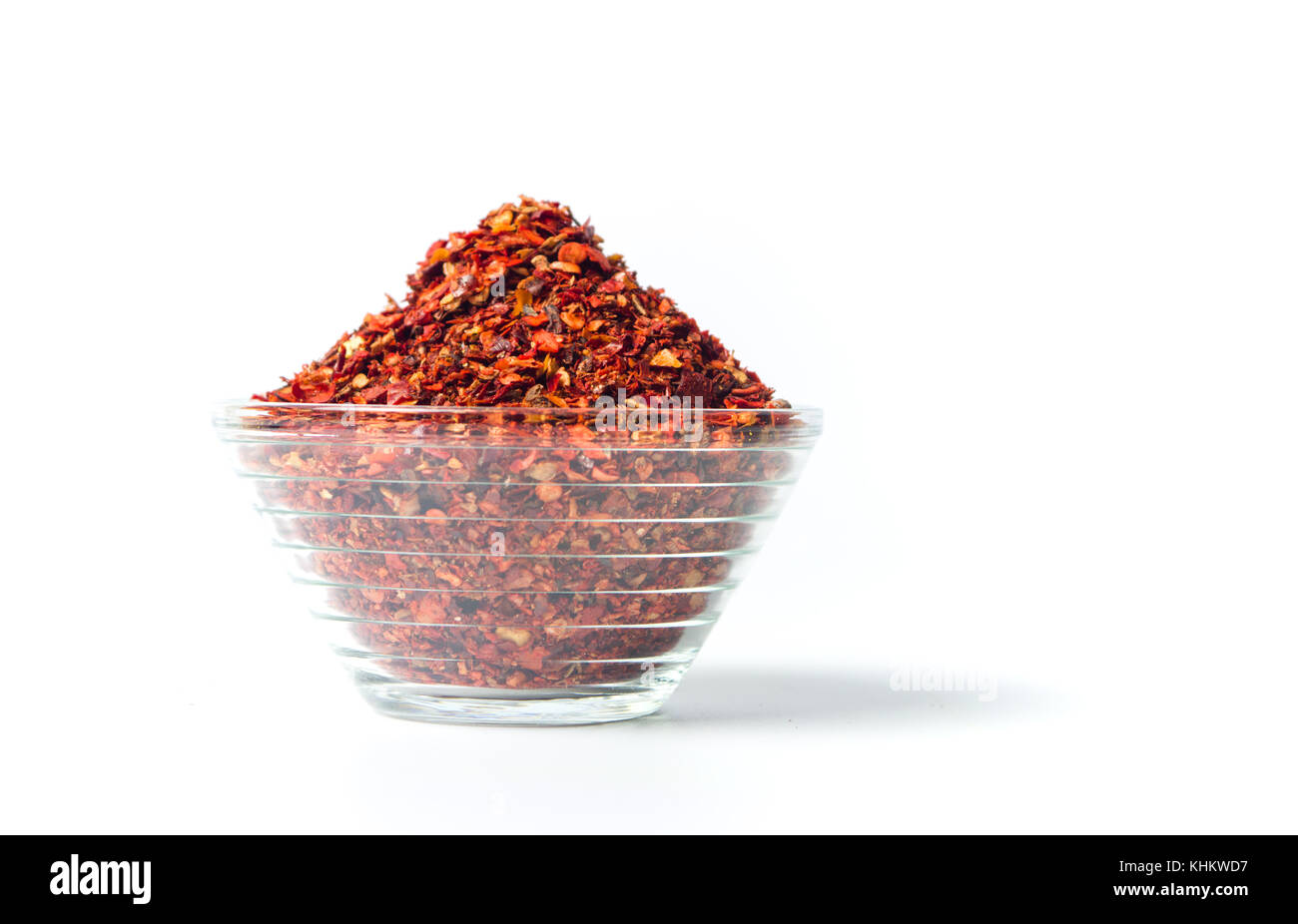 Poudre de piment rouge écrasé dans un bol en verre isolé Banque D'Images