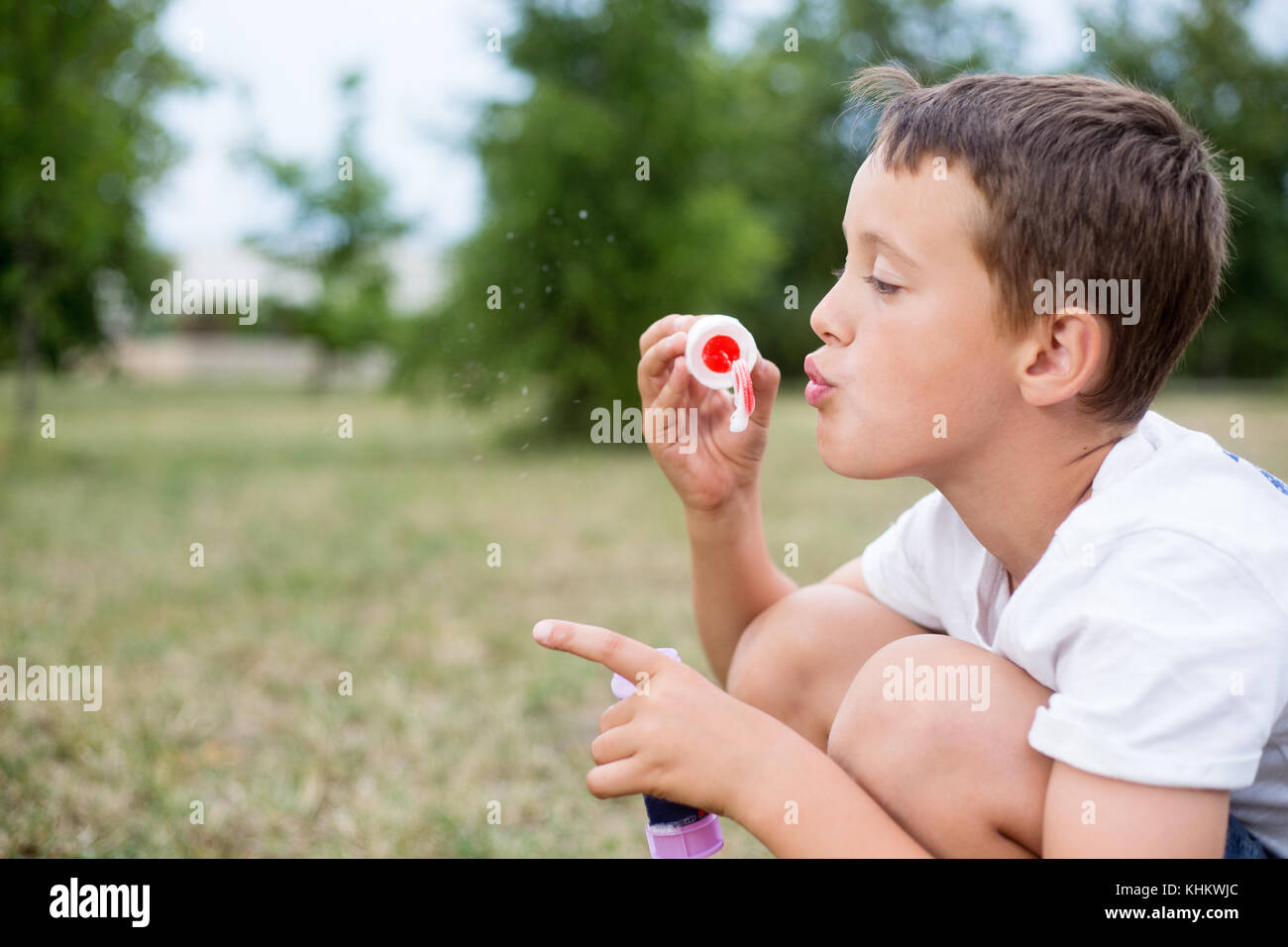 Close-up portrait of cute orientale petit boy blowing bubbles outdoors dans un parc à jour d'été Banque D'Images