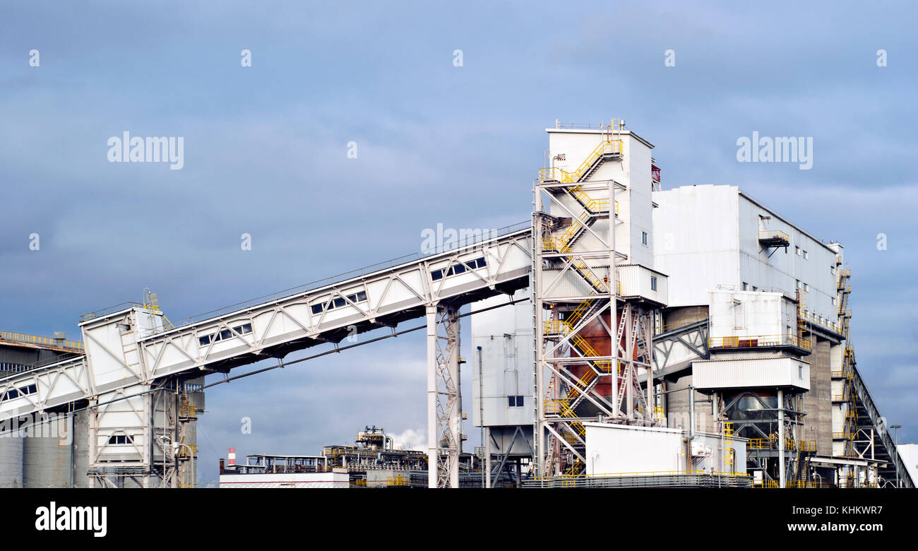 Un fragment d'une entreprise industrielle moderne avec plusieurs silos pour le stockage de matériaux en vrac et d'un convoyeur à bande incliné couvert Banque D'Images