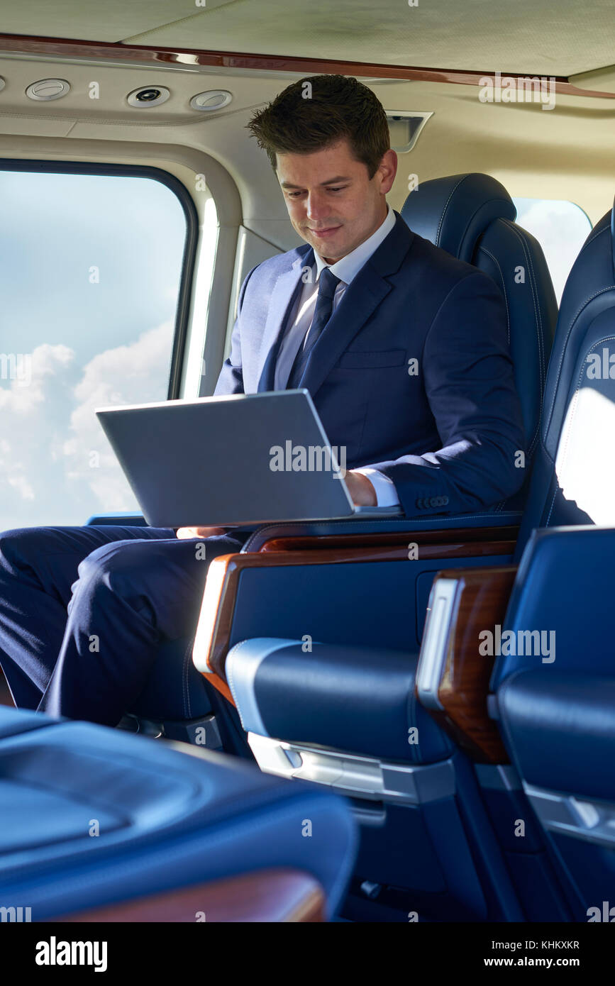 Businessman working on laptop in cabine de l'hélicoptère pendant le vol. Banque D'Images