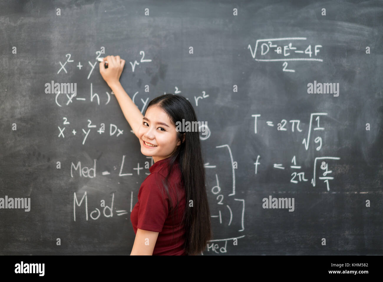 Belle asiatique student writing on blackboard with chalk en classe. Banque D'Images
