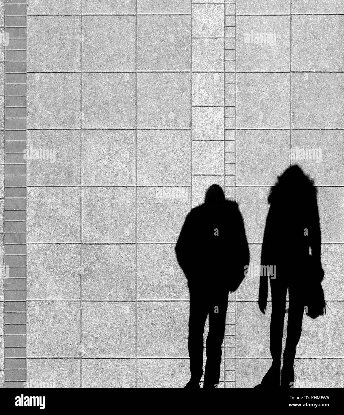 Ombre d'un jeune couple en train de marcher sur le trottoir de la rue de la ville d'en haut en noir et blanc Banque D'Images