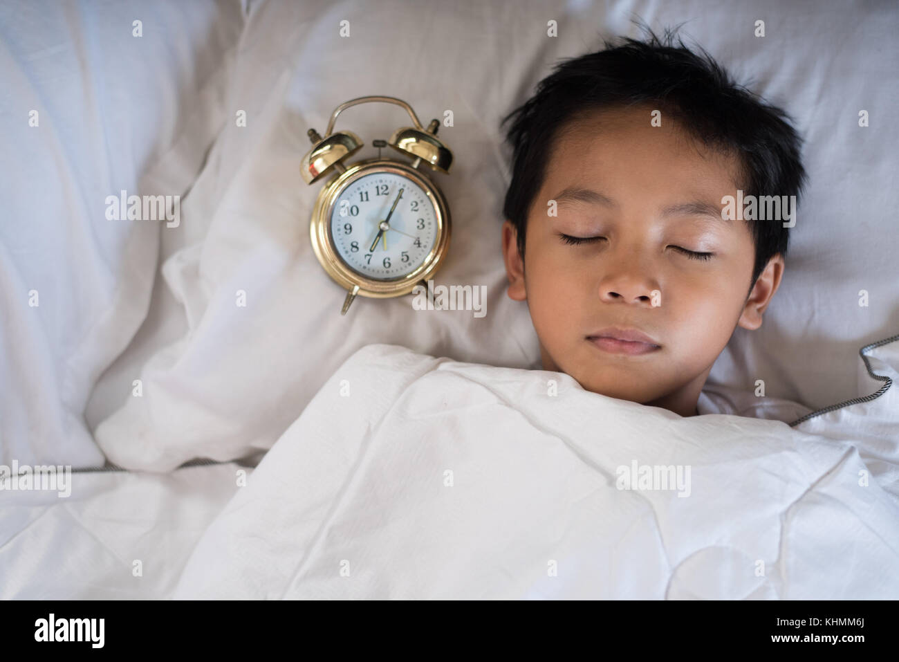 Jeune garçon endormi avec réveil sur le lit au matin.asian boy s'endormir.sleep concept Banque D'Images