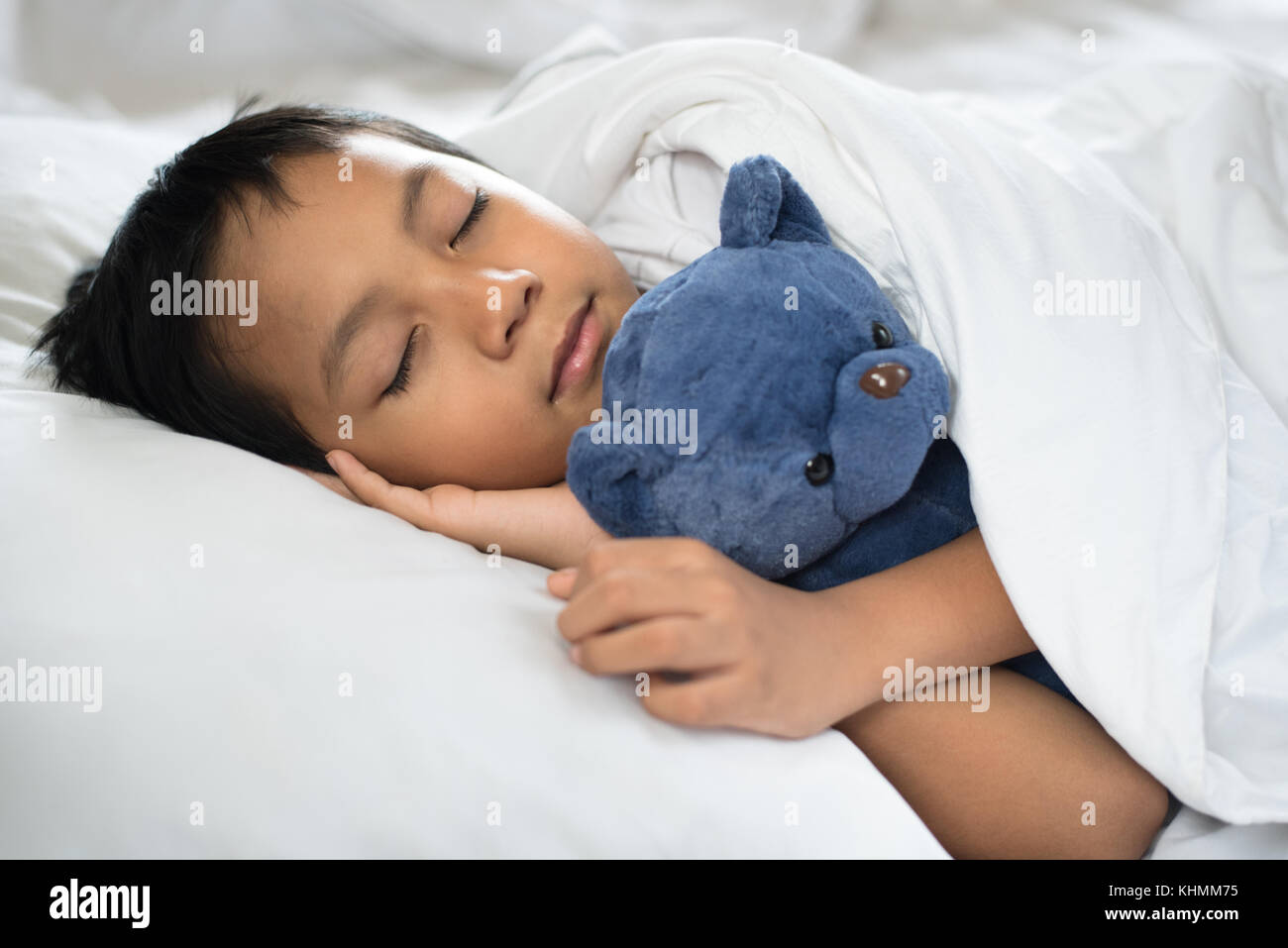 Le garçon endormi sur le lit avec ours blanc oreiller et draps.boy s'endormir dans matin.sleep concept Banque D'Images