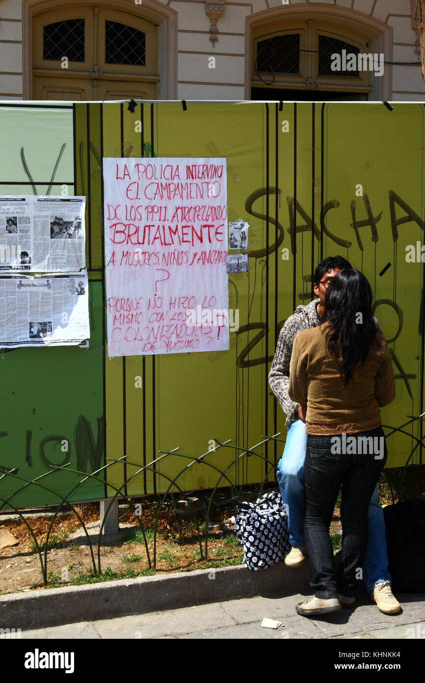 Couple à côté d'une affiche pour demander pourquoi la police bolivienne a brutalement fait irruption le TIPNIS road camp de protestation à Chaparina près de Yucumo, Bolivie Banque D'Images