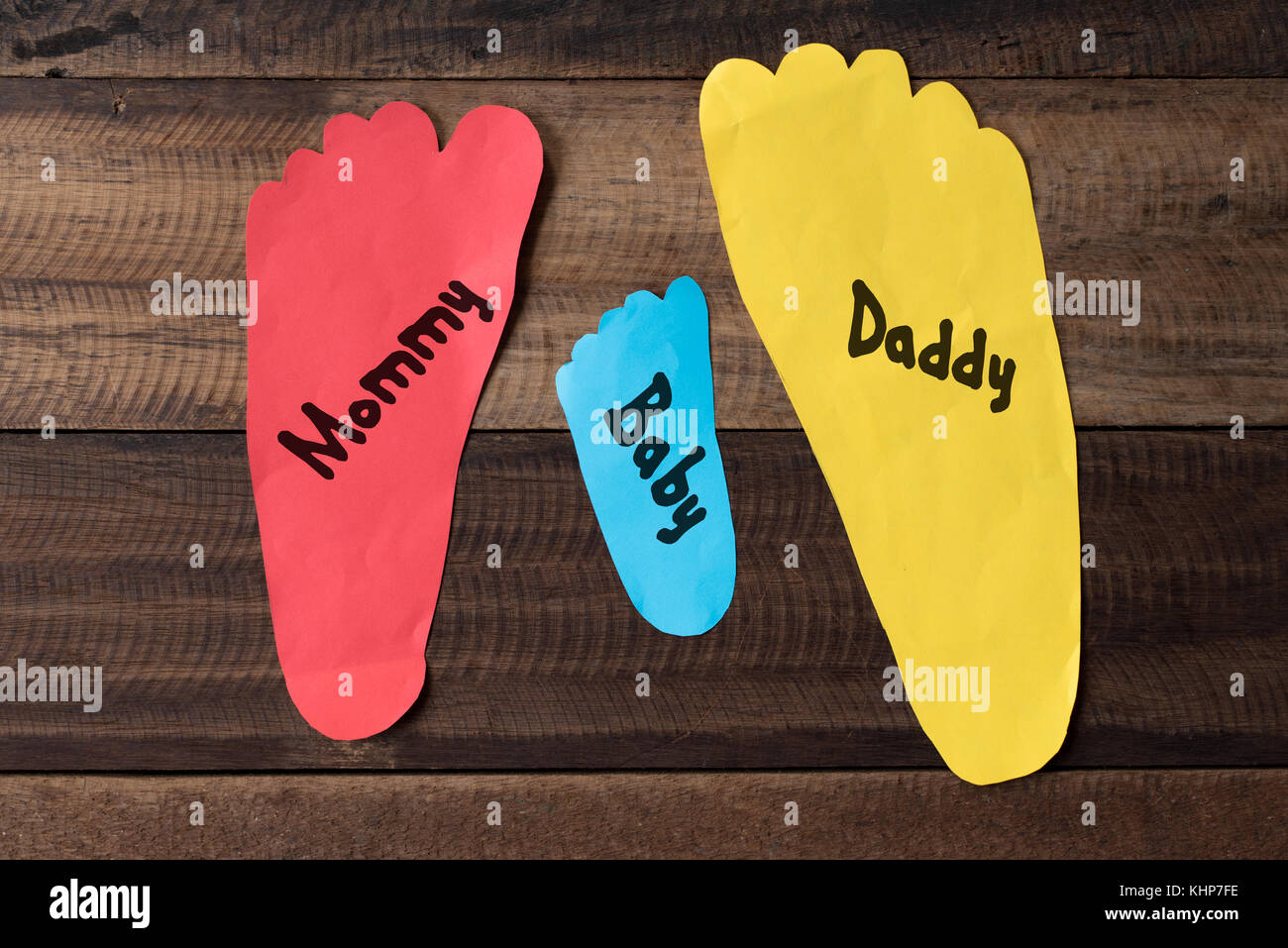 Mesure de la famille de leurs pieds en papier colorés sur fond de bois.family concept.pied papier écrit "maman, papa et bébé' Banque D'Images