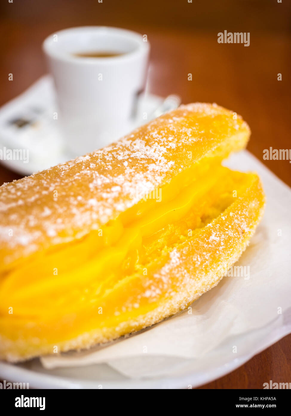 Donut portugais ou Berliner avec oeuf et crème de café sur la table en bois brun dans une Pastelaria Banque D'Images