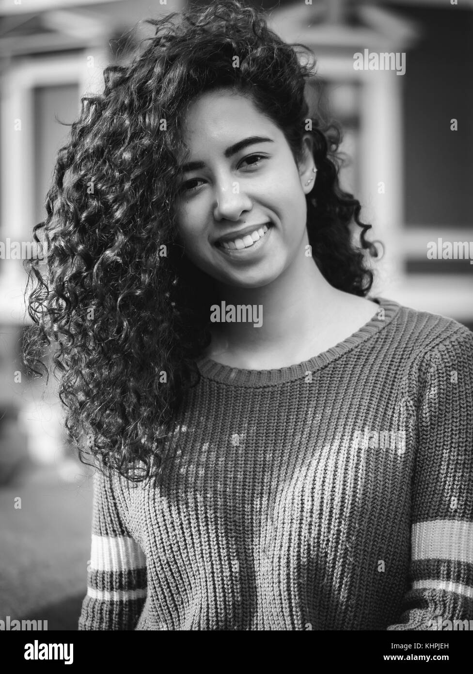 Portrait of happy young hispanic woman avec de beaux cheveux bouclés dans la rue. mixed race girl smiling. saison d'automne. couleur à l'automne, l'architecture rouge Banque D'Images