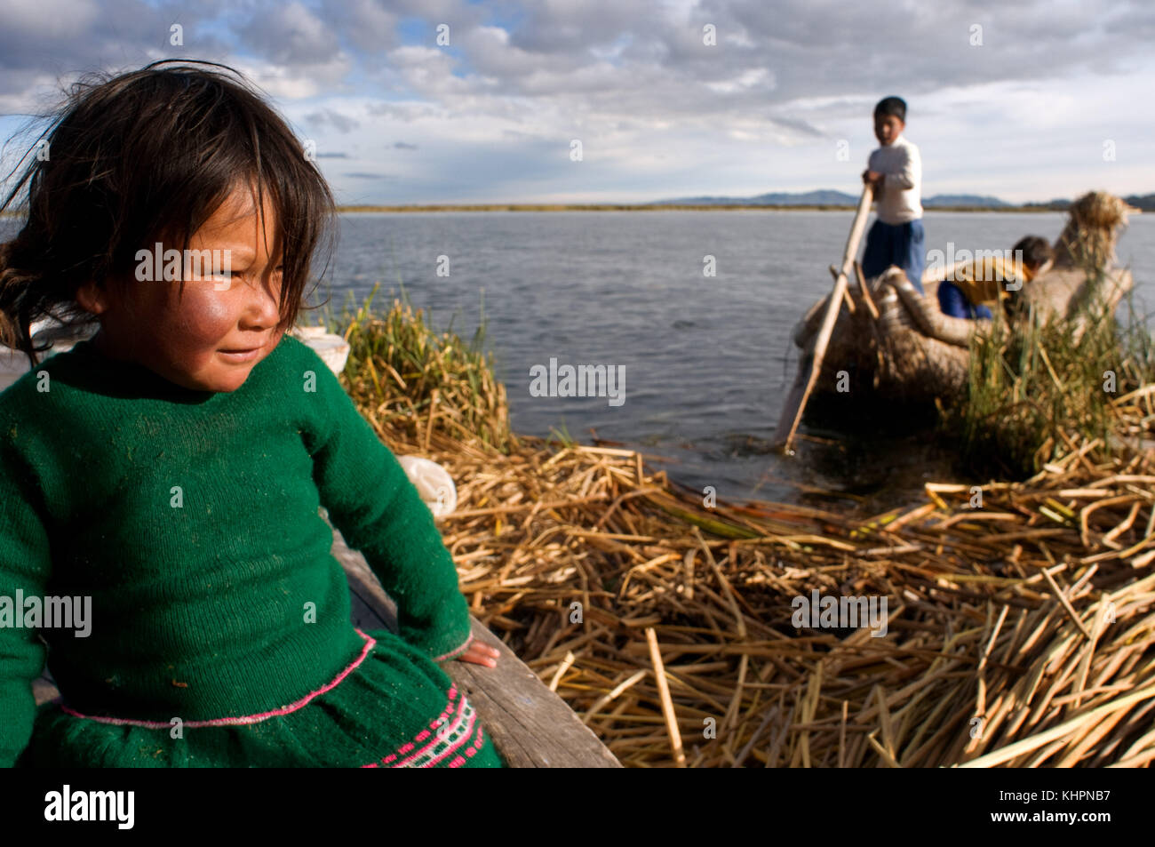 L'île uros, le lac Titicaca, au Pérou, en Amérique du Sud. Les enfants de naviguer dans un bateau sur le lac Titicaca totora près d'une île habitée par des Uros. Banque D'Images