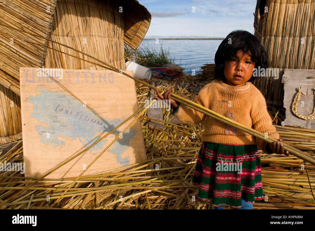 L'île uros, lac Titicaca, Pérou, Amérique du Sud. une fille sur l'île de los Uros situé à l'intérieur du lac Titicaca joue avec un roseau totora. Banque D'Images