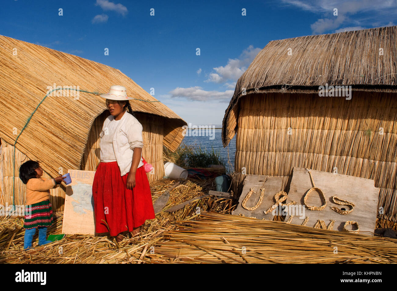 L'île uros, lac Titicaca, Pérou, Amérique du Sud. une femme et de sa fille sur une île de l'Uros. ces îles sont construites sur un sol totora vegetati Banque D'Images