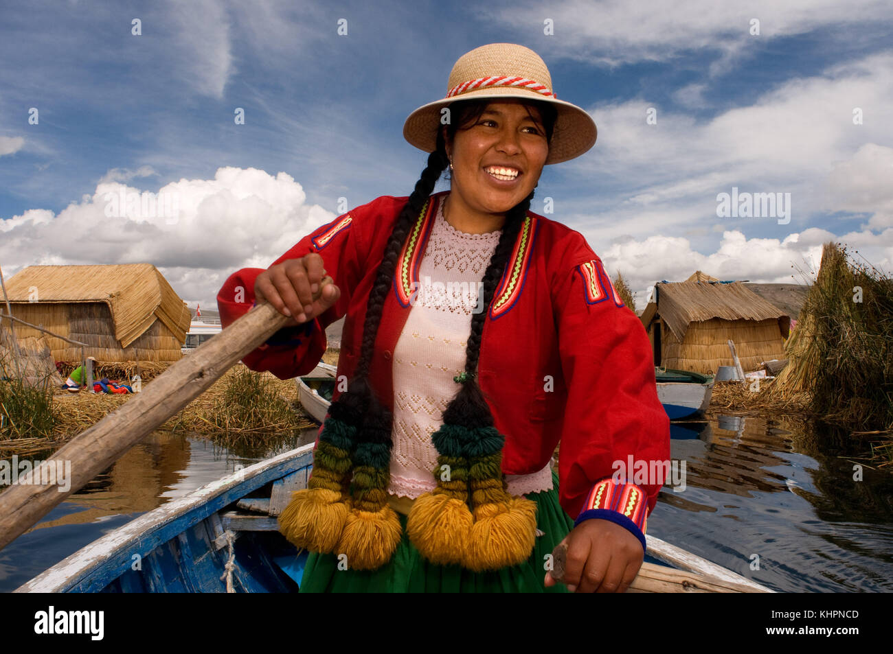 L'île uros, lac Titicaca, Pérou, Amérique du Sud. une femme vêtue de voiles robes traditionnelles de la région son bateau entre les îles Uros. Banque D'Images