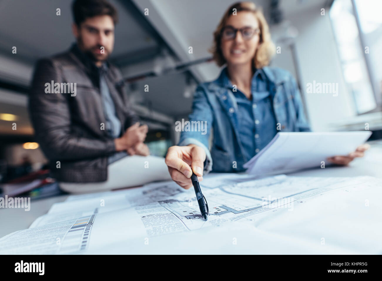 Les concepteurs travaillant sur blueprint sur table en bureau. Se concentrer sur les main pointant sur le dessin. Banque D'Images