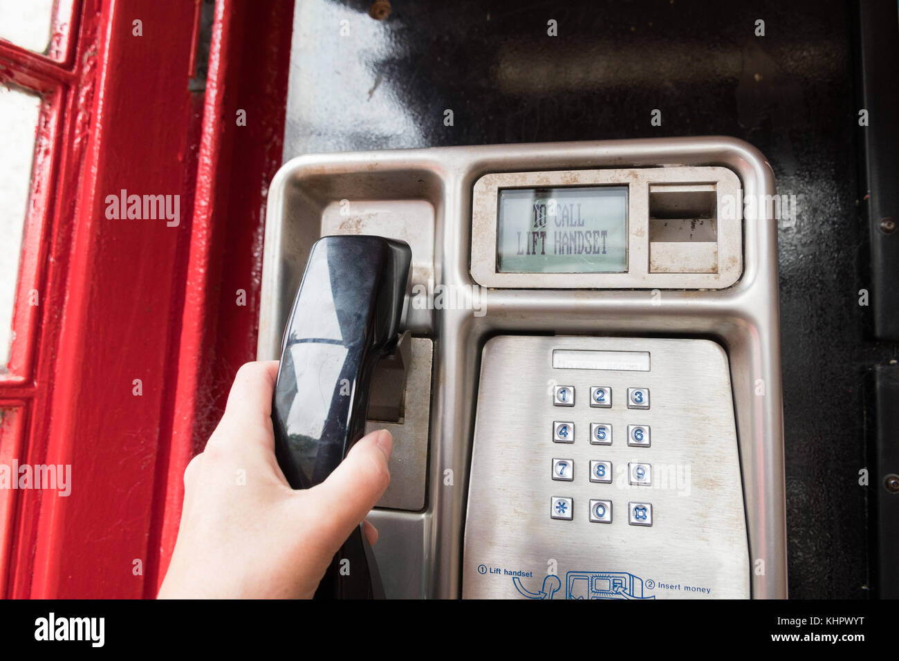 Utilisation d'un téléphone public BT dans une boîte téléphonique rouge Banque D'Images