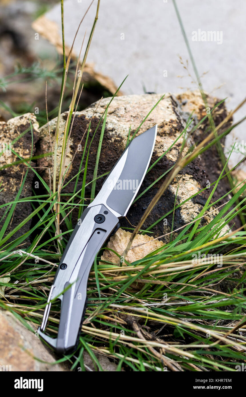 Couteau de poche avec une carabine. Couteau photo dans la nature. Tir vertical. Banque D'Images