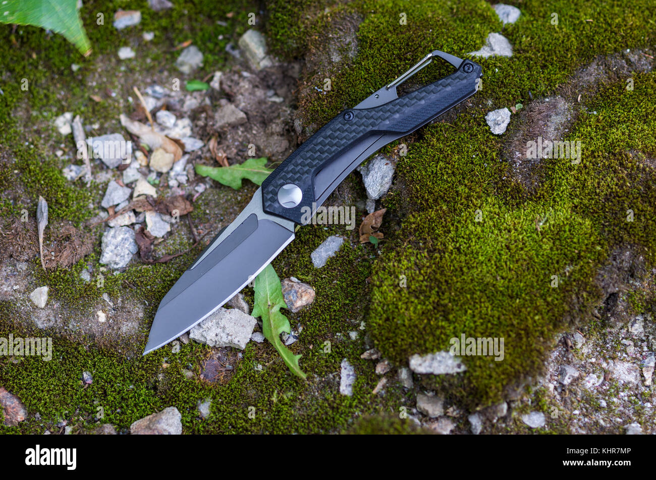 Un couteau de poche avec une poignée noire et une lame noire. Photo sur la nature. Banque D'Images