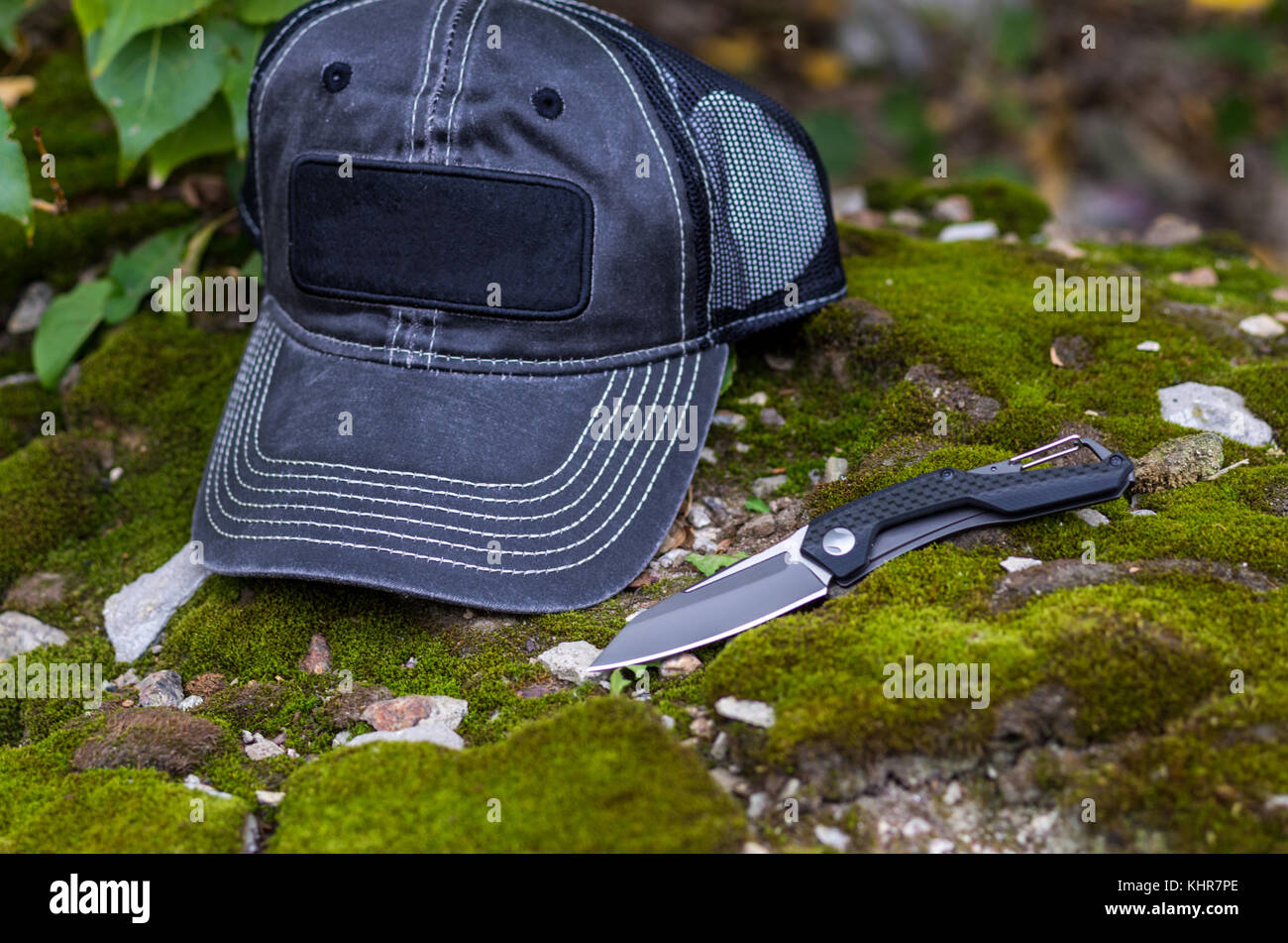 Couteau pliant noir et noir Casquette de baseball. Photo sur le fond de mousse. Banque D'Images