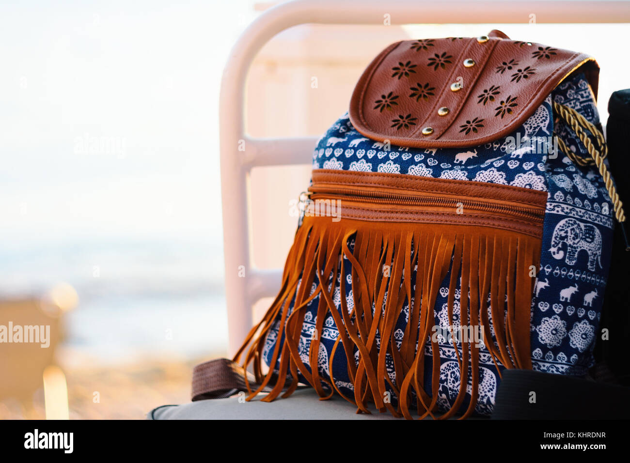 Vue avant du sac à dos bleu hipster avec motif éléphant blanc et franges en cuir sur une chaise à côté de la plage Banque D'Images
