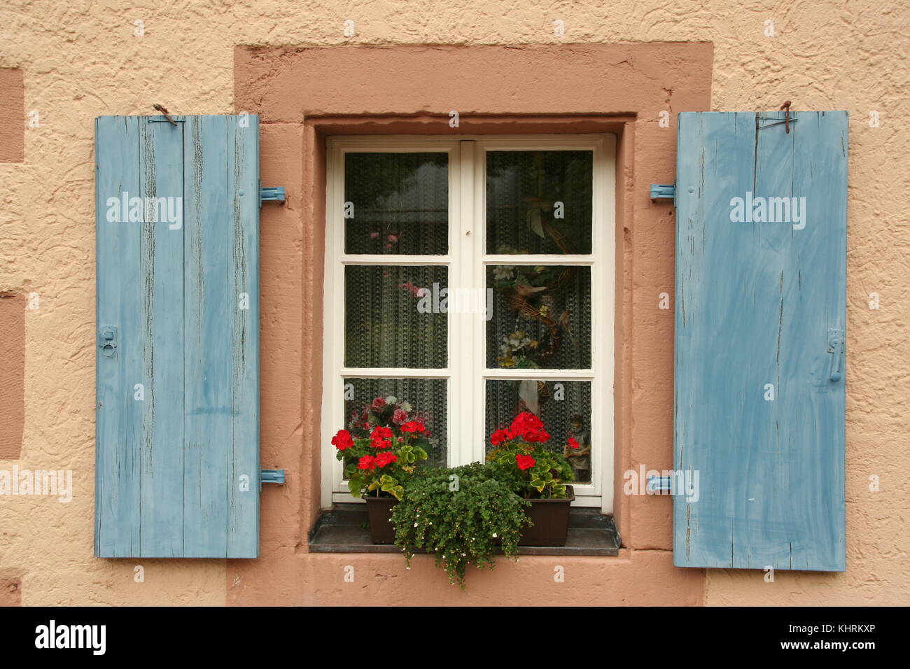 Belle fenêtre avec des volets bleus sur un mur rose et fleurs , Forêt Noire, Allemagne Banque D'Images