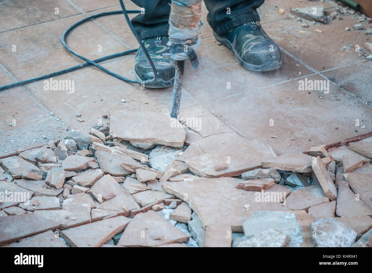 Terrasse étage élevé, dans des œuvres de placer sous elle wtaerproofing et un travailleur dans l'foregournd avec un outil de perçage béton Banque D'Images