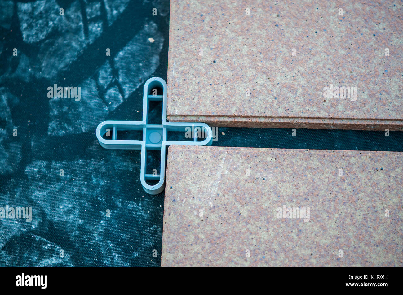 L'installation de tuiles sur une terrasse étage avec morceau de plastique avec croix de laisser un espace entre les tuiles et certains déjà butyle placé au dessous de t Banque D'Images