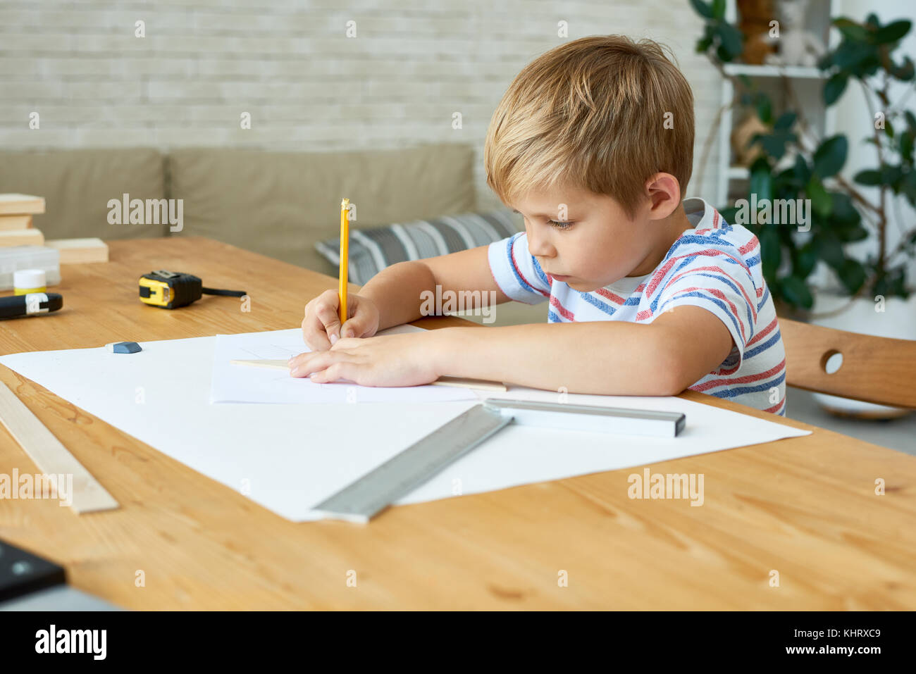Portrait of cute little boy écrire ou dessiner soigneusement assis à un bureau et à faire leurs devoirs, copy space Banque D'Images